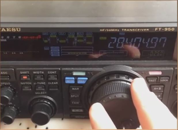 a hand dialing a VFO knob on a transceiver